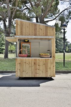 a small food cart sitting on the side of a road next to a tree and grass field