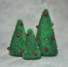 three small green christmas trees with red berries on the top and gold trimmings