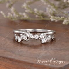 a silver ring with leaves and flowers on it sitting on top of a wooden table