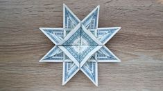 an origami star made out of dollar bills on a wooden table with wood grains