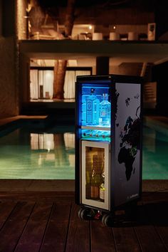 a cooler sitting on top of a wooden floor next to a swimming pool at night