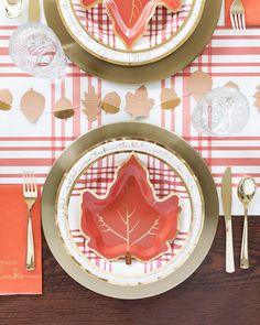 the table is set with gold and red plates, silverware, and napkins