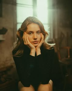 a woman sitting down with her hands on her face