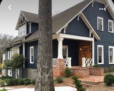 a blue house with white trim on the front door and porch, surrounded by trees