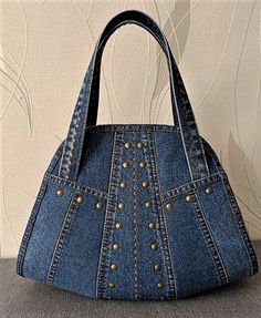 a denim purse with rivets on the front and sides, sitting on a table