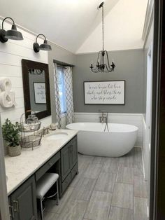 a large white bath tub sitting under a chandelier in a bathroom next to a sink