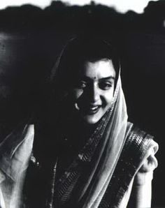 black and white photograph of a woman in sari smiling at the camera with her hand on her hip