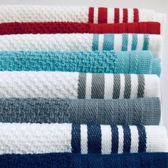 towels folded neatly on top of each other in different colors and patterns, all lined up side by side