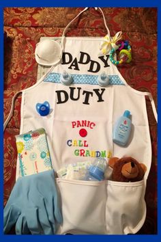 an apron that says, daddy duty with baby items in it and a teddy bear