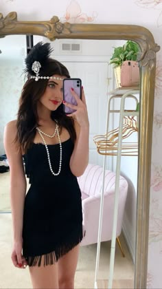 a woman taking a selfie in front of a mirror wearing a black flap dress