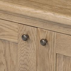 a close up view of the handles on a wooden cabinet with two knobs in it