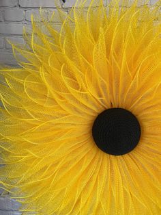 a large yellow flower with black center surrounded by feathers