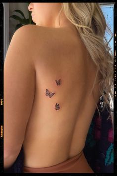 the back of a woman's body with three butterflies on her left side tattoo