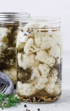 two jars filled with cauliflower on top of a table