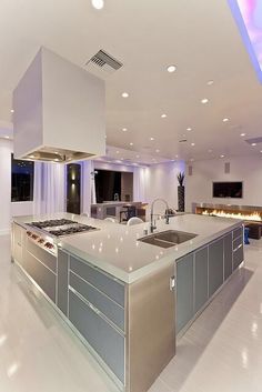 a large kitchen with stainless steel appliances and white counter tops, along with an island in the middle