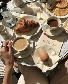 a table full of breakfast foods and drinks on it's side, including croissants