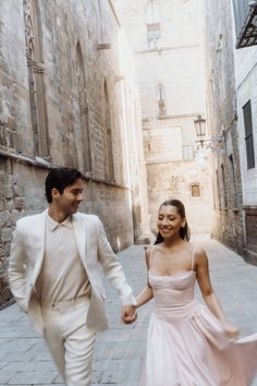 a man and woman walking down an alley way holding hands in front of each other