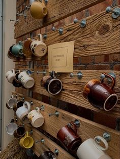 there are many cups and mugs on the wall with magnets attached to it