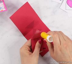 someone is making a valentine's day card out of red paper and some glue