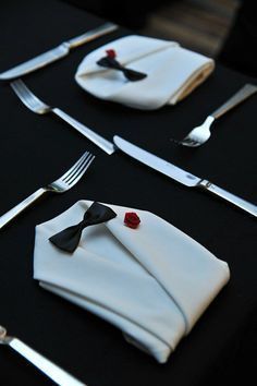 a black table topped with white napkins and silverware