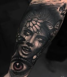 a woman's arm with an evil face and eye tattoo on the left forearm