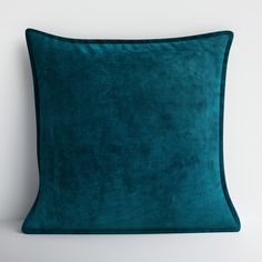 a teal green velvet pillow on a white background with the corner of the pillow