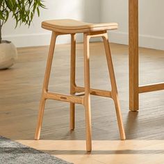 a wooden stool sits in front of a table with a potted plant on it