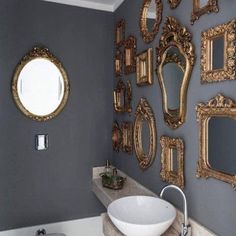 a bathroom with several mirrors on the wall and a sink in front of an oval mirror