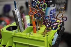 scissors, combs and other office supplies are arranged in a holder on a desk