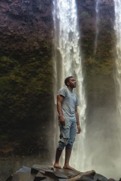 a man standing in front of a waterfall