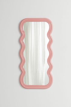 a pink scallop mirror on a white wall