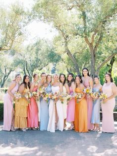 a group of women standing next to each other in long dresses and holding bouquets