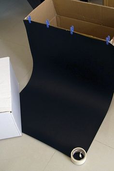 an open cardboard box with tape on the floor next to it and a black board