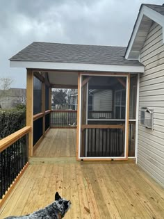 a dog standing on a wooden deck in front of a house with a screened porch