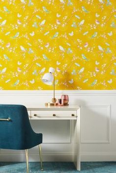 a blue chair sitting next to a white desk in front of a yellow wallpaper