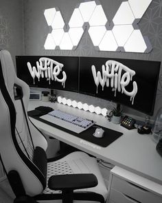 a computer desk with two monitors and a keyboard on it, covered in white graffiti