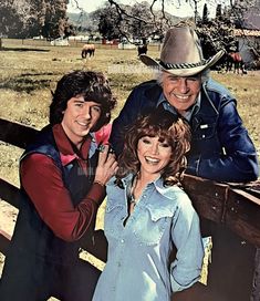 two men and a woman posing on a fence