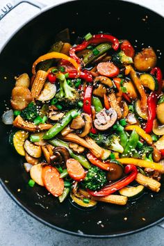 stir fry with broccoli, carrots, mushrooms and other vegetables in a wok