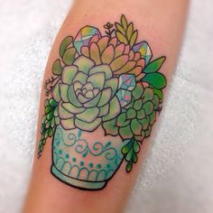 a flower pot with succulents and leaves on the side of someone's leg