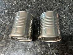 two metal canisters sitting on top of a granite counter