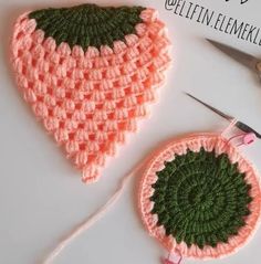 two crocheted potholders are sitting on a table next to scissors and yarn