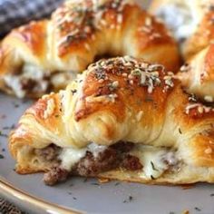 several sausage rolls on a plate with cheese and herbs sprinkled on top, ready to be eaten