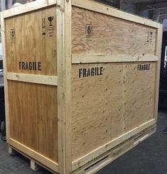 two large wooden crates sitting on top of each other in a warehouse or workshop area