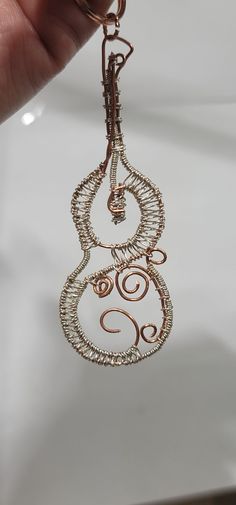 a hand holding a wire wrapped keychain that is shaped like a spiral design