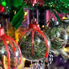 three glass ornaments with red ribbon hanging from the top and green grass in between them