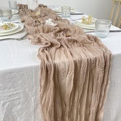 the table is set with white plates and silverware, along with napkins that have been draped over them