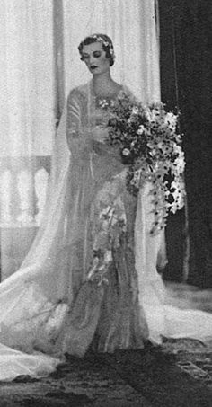 an old black and white photo of a woman in a wedding dress holding a bouquet