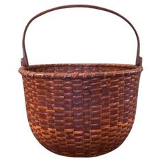 a brown woven basket is shown on a white background, with the handle extended to it's side