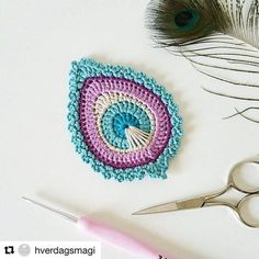 a crocheted doily with scissors next to it and some feathers on the table