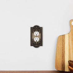 a wooden cutting board sitting on top of a table next to a wall mounted light switch